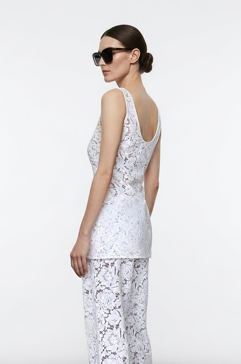Woman wearing a white lace outfit against a plain background