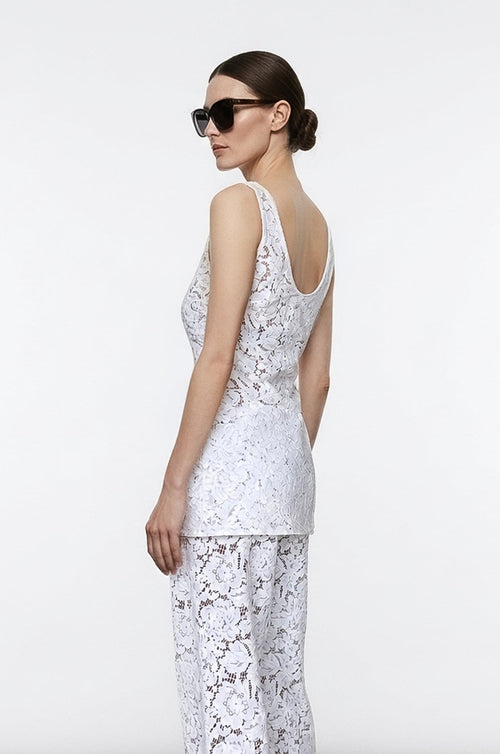 Woman wearing a white lace outfit against a plain background