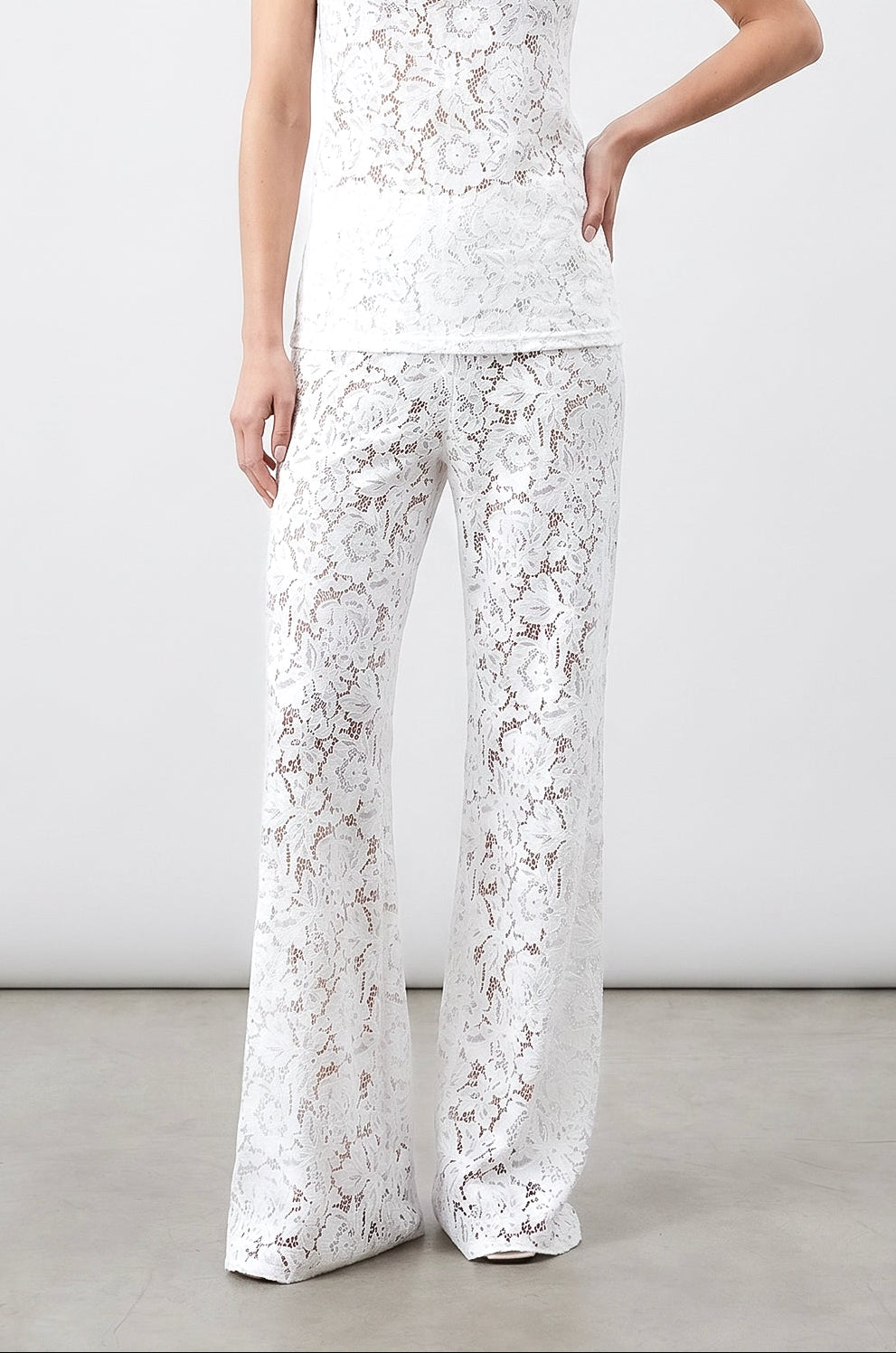 Woman wearing a white lace outfit against a plain background